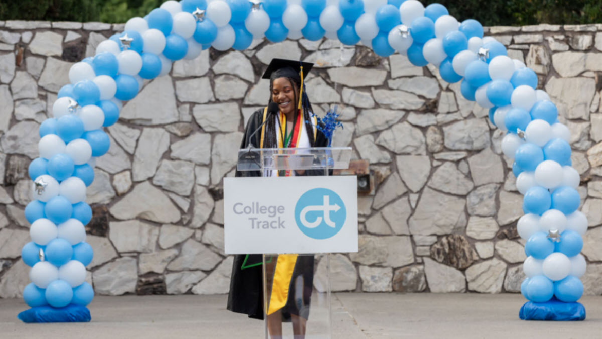 Student college graduate on a stage with balloon arch