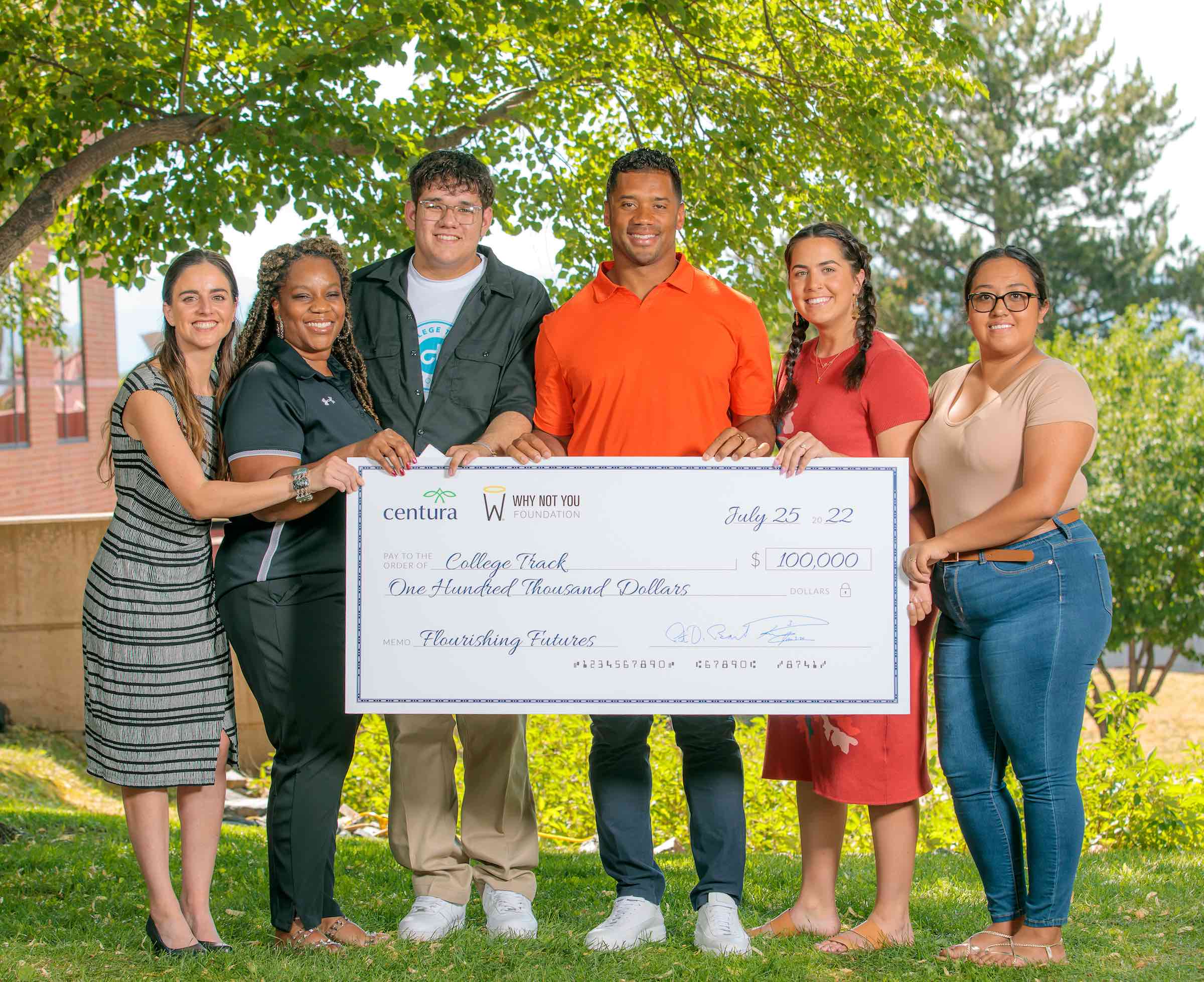 Russell Wilson and College Track staff holding a check
